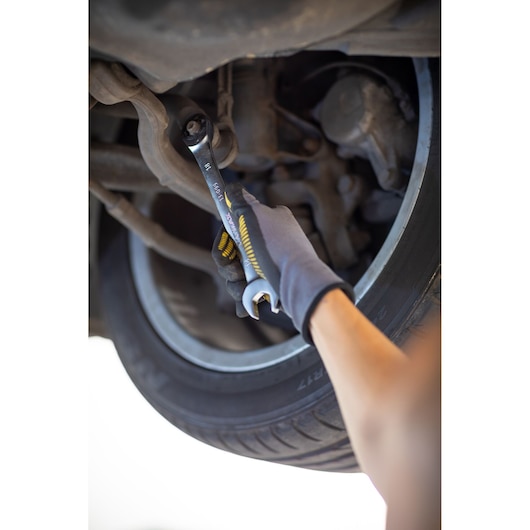 STANLEY FMMT82849-0 steeksleutel gebruikt op autosuspensie, close-up met gehandschoende hand en band.