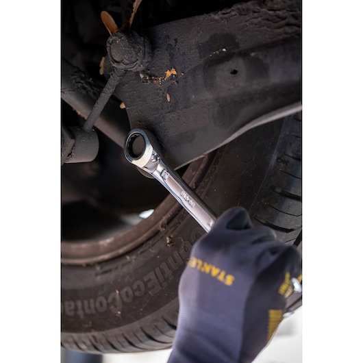 Foto van STANLEY FMMT82849-0 ratelsleutel in gebruik op autoschroef, monteur draagt STANLEY handschoenen.