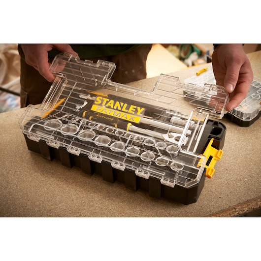STANLEY FMMT98103-1 organizerbox met doorzichtige deksel en FATMAX logo, vastgehouden op werkbank.