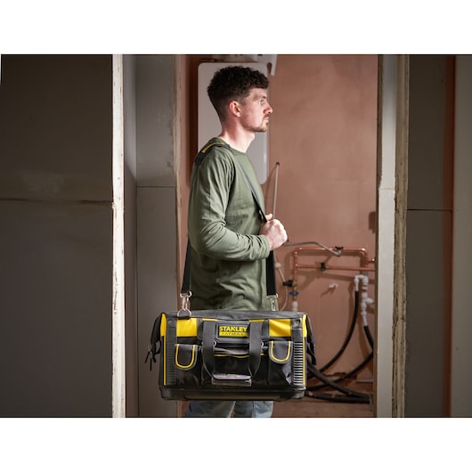 STANLEY FMST1-71180 sac à outils avec bandoulière, noir et jaune, porté par une personne dans un environnement de travail.