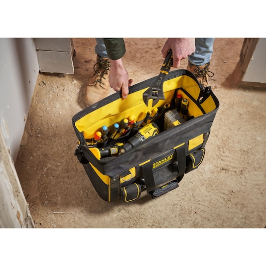 STANLEY FMST1-71180 sac à outils rempli d’outils à main et accessoires, vue de dessus, sur sol de chantier.