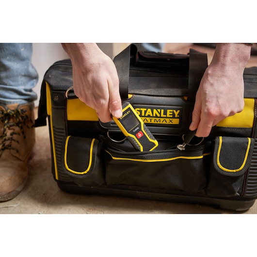 STANLEY FMST1-71180 sac jaune et noir, poche avant ouverte, personne insérant un outil STANLEY.