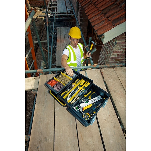 Boîte à outils STANLEY FMST1-71219 ouverte sur chantier avec outils à main et fixations assortis.