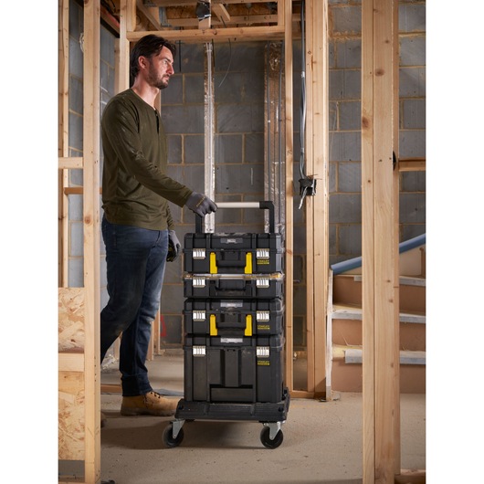 STANLEY FMST1-71972 chariot porte-outils empilable avec poignée télescopique et loquets jaunes, présenté sur un chantier.