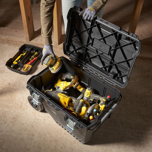STANLEY FMST1-73601 photographie d'une boîte à outils noire à roulettes ouverte, remplie d'outils électriques jaunes, vue du dessus.