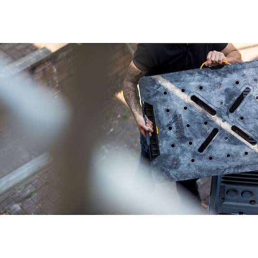 STANLEY FMST1-75672 zwarte opvouwbare werkbank met gele handgreep, buiten gedragen.