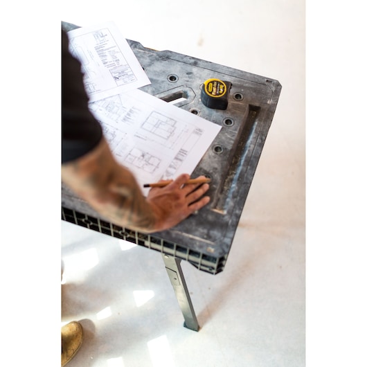 Foto van de STANLEY FMST1-75672 werktafel met bouwtekeningen en rolmaat erop, schuin van boven genomen.