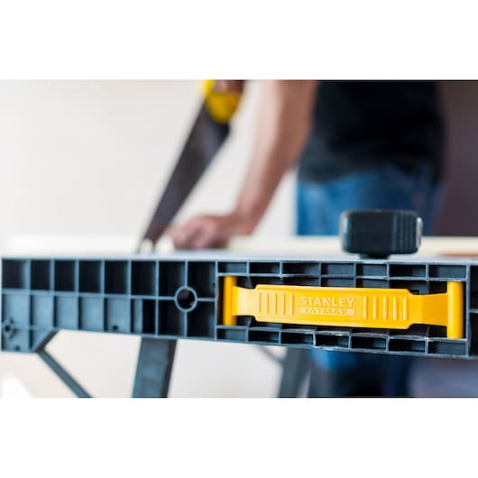 Stanley FMST1-75672 zaagbok close-up, gele Fatmax hendel, gebruiker vaag hout zagen.
