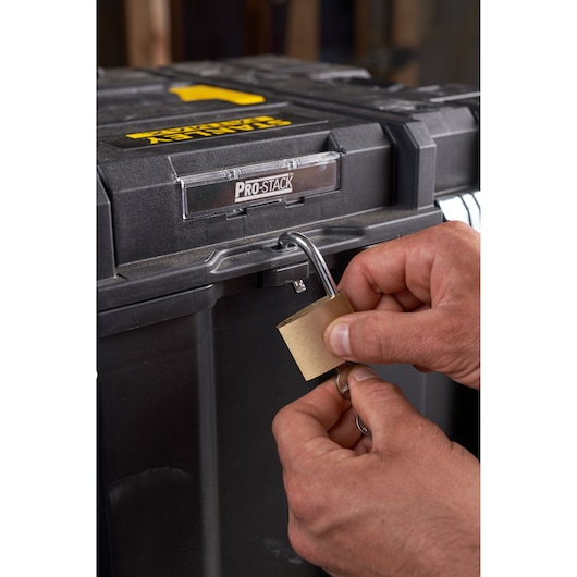 Foto van STANLEY FMST1-75753 gereedschapskist met PRO-STACK-label, close-up van handen die vergrendelen met hangslot.