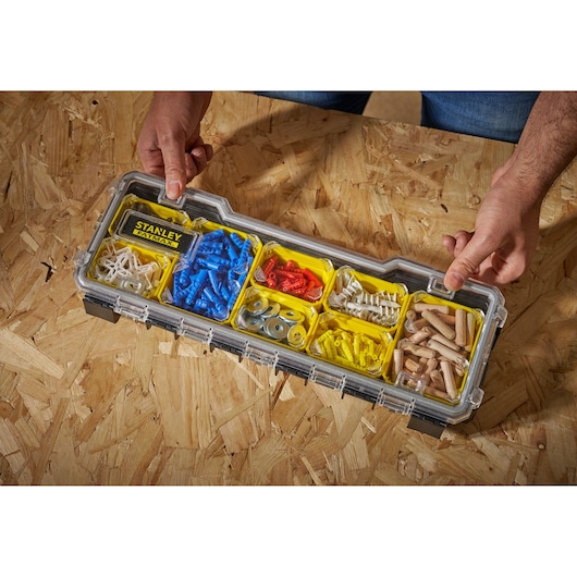 Boîte organisateur STANLEY FMST1-75781 avec attaches en plastique et métal assorties, vue de dessus, mains tenues.
