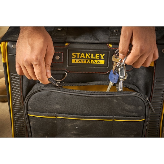 Foto van STANLEY FMST1-80148 Fatmax gereedschapstas met handen die sleutels aan de voorkeerring bevestigen, close-up.