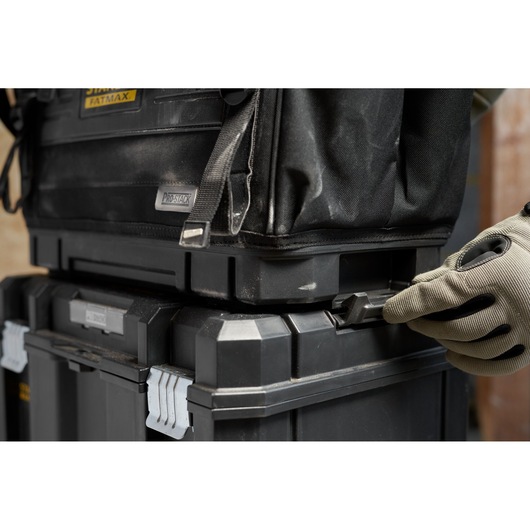 STANLEY FMST17626-1 boîtes à outils empilables noires avec loquet latéral manipulé, vue rapprochée.