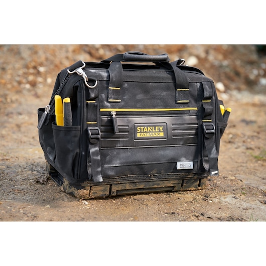 STANLEY FMST17627-1 sac à outils avec bordures jaunes et poches, photographié sur terre en extérieur.
