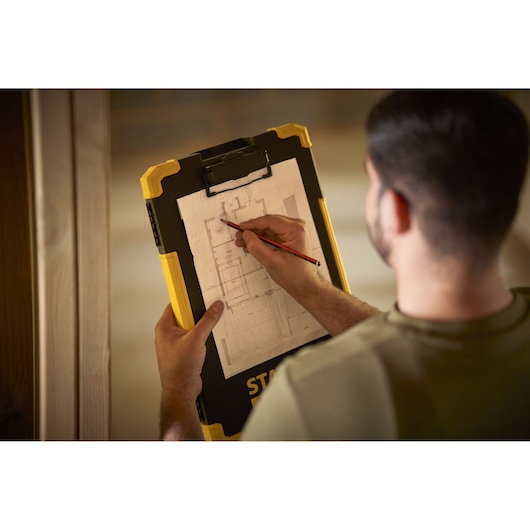 STANLEY FMST82721-1 klembord vastgehouden door persoon die op bouwtekening schetst, productfotografie.