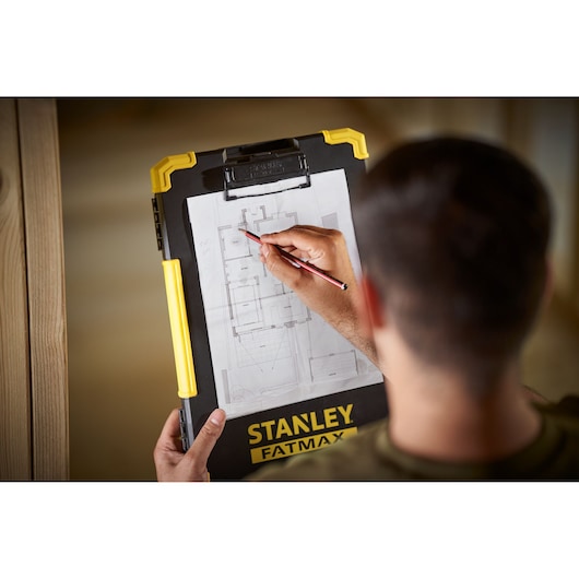 Porte-bloc STANLEY FMST82721-1 avec poignée jaune, utilisé pour annoter un plan architectural.