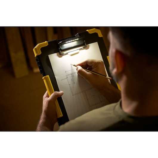 STANLEY FMST82721-1 klembord met ingebouwde LED-lamp, gebruikt voor bouwtekening, schuin in de hand.