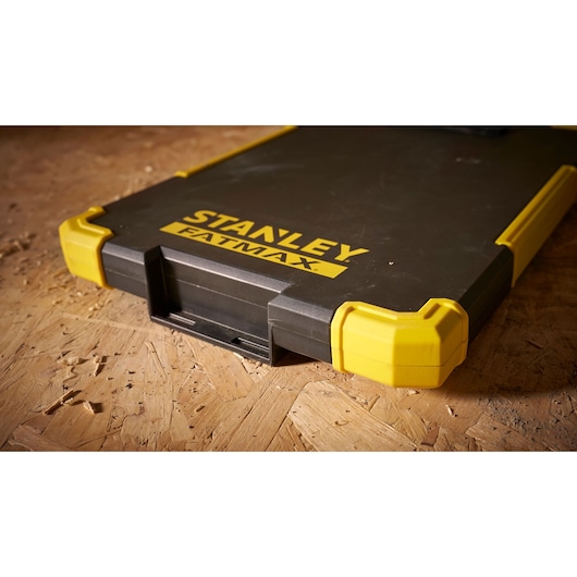 Boîte à outils Stanley FMST82721-1 avec coins renforcés jaunes, photographie en gros plan sur surface bois.