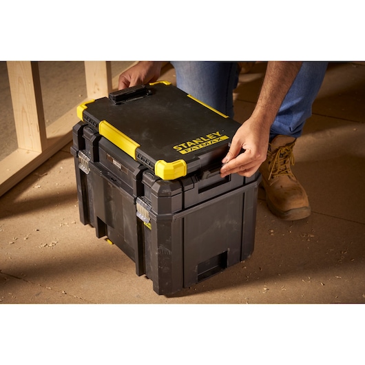Photo du coffre de rangement pour outils noir et jaune STANLEY FMST82721-1, verrouillé sur chantier.