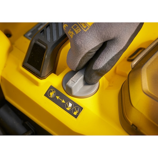 STANLEY SCMWP3701M2 bouton de commande tondeuse, gros plan sur surface jaune, main gantée