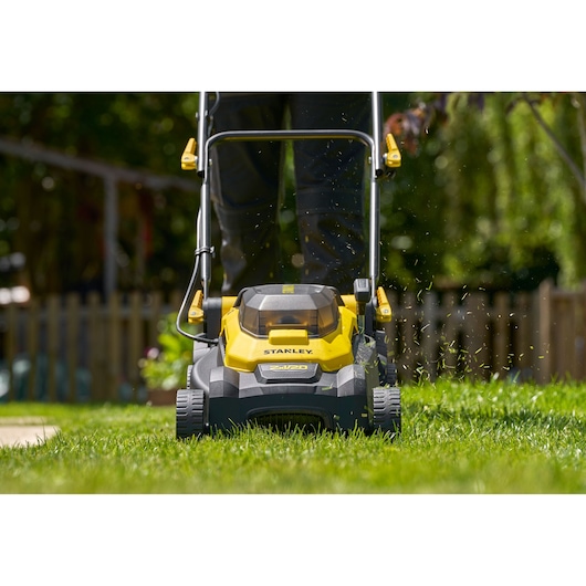 Tondeuse Stanley SCMWP3701N vue de face en utilisation, design jaune et noir sur pelouse verte extérieure.