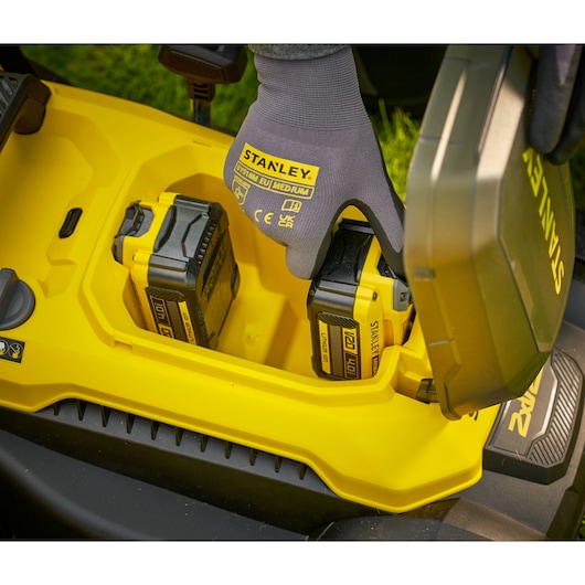 STANLEY SCMWP3701N photographie d’un compartiment batterie jaune avec gants STANLEY installant des batteries lithium