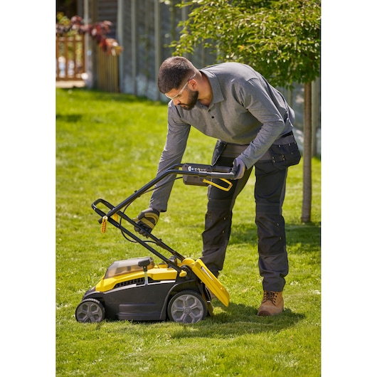 Tondeuse Stanley SCMWP3701N jaune et noire utilisée sur l’herbe verte à l’extérieur.