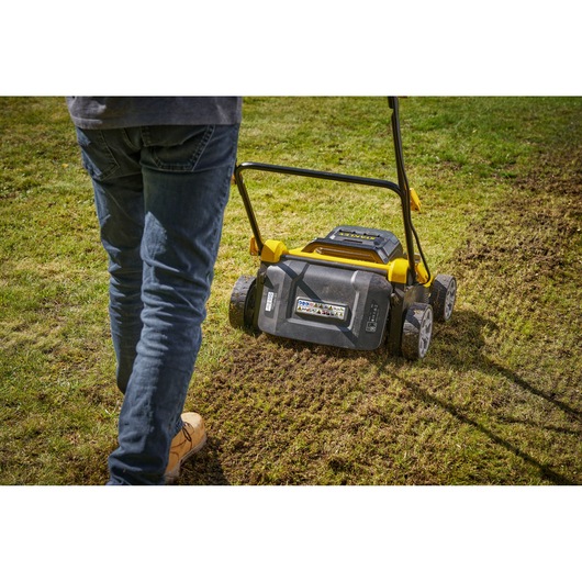 STANLEY SCOEP3801M2 gazonschar in gebruik op gras, achteraanzicht met wielen en handvat.