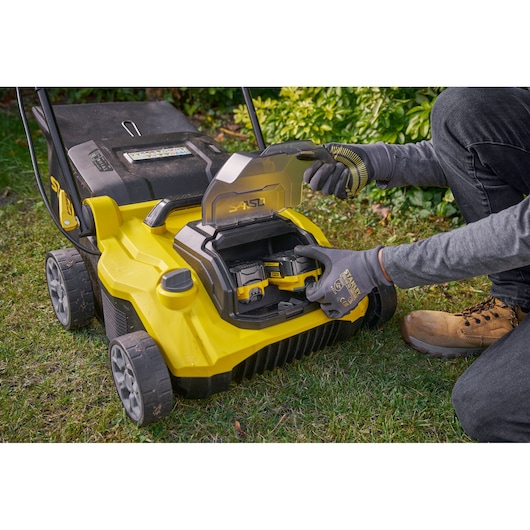 STANLEY SCOEP3801M2 gele grasmaaier, close-up van accuvak met batterijplaatsing buiten.