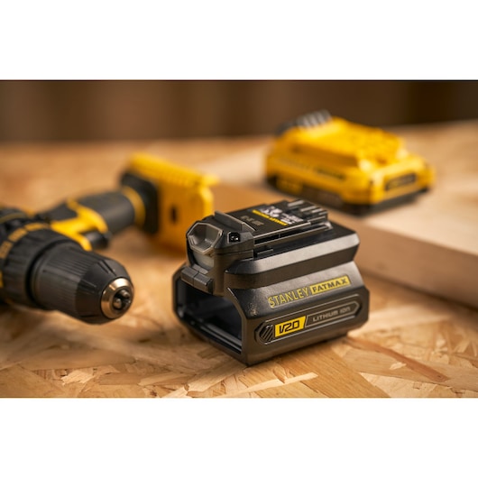 STANLEY SFMCB100 V20 lithium-ion batterij, close-up op werkbank, boormachine en oplader op de achtergrond.