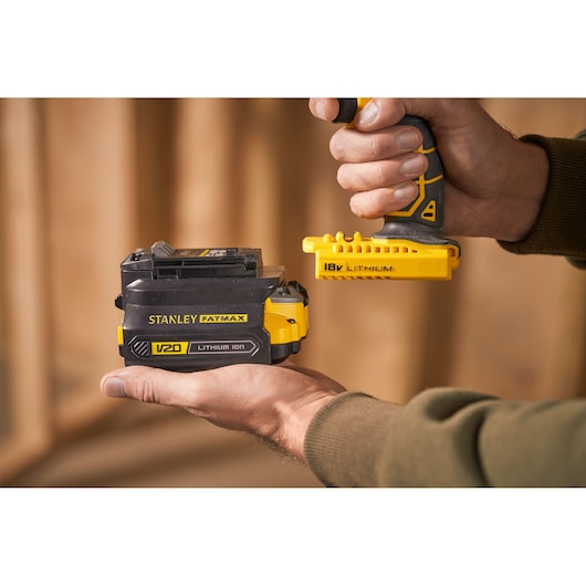 Foto van STANLEY FATMAX V20 lithium-ion batterij, SKU SFMCB100, vastgehouden in de hand, met 18V lithium gereedschapconnector.