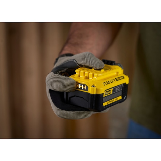 Foto van STANLEY SFMCB14M1 V20 4,0Ah lithium-ion batterij in een gehandschoende hand.