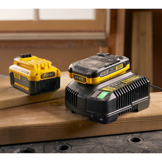 Foto van STANLEY SFMCB14 V20 lithium-ion batterij en oplader op hout, werkplaats achtergrond.
