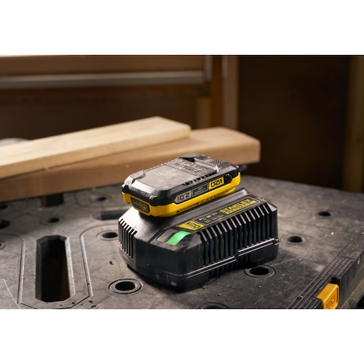 STANLEY SFMCB202 batterij en oplader met gele accenten op werkbank, vooraanzicht.