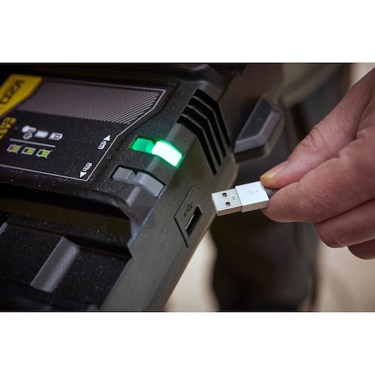 STANLEY SFMCB24 acculader met groene indicator en persoon die USB-kabel aansluit, close-up.