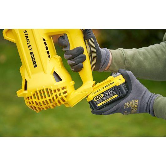 Foto van STANLEY SFMCBL714M1 bladblazer met V20 4.0Ah batterij die wordt geplaatst, close-up buiten.