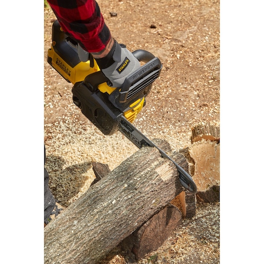 Tronçonneuse sans fil STANLEY SFMCCS630B découpant une bûche, présentée en utilisation extérieure.