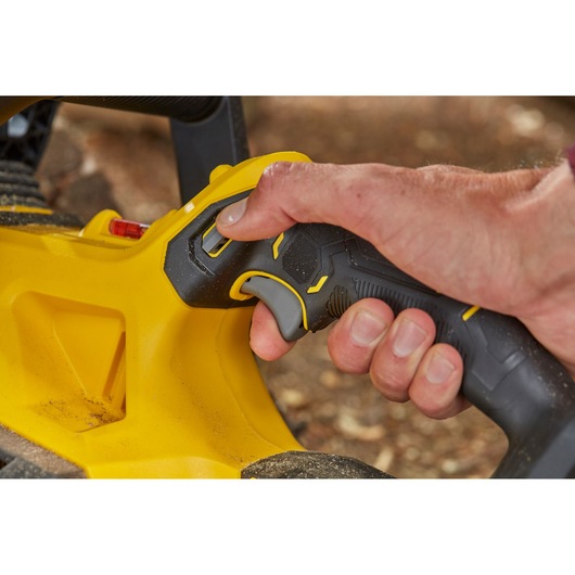 STANLEY SFMCCS630B gros plan sur la poignée noire et jaune de l’outil électroportatif, main tenant la gâchette.