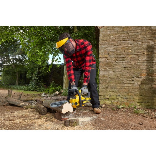 Photo de la tronçonneuse STANLEY SFMCCS630B utilisée en extérieur pour couper des bûches, opérateur équipé.