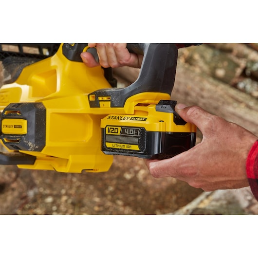 Photo de la tronçonneuse STANLEY SFMCCS630M1 V20 Fatmax avec batterie lithium-ion 4,0 Ah insérée en extérieur.
