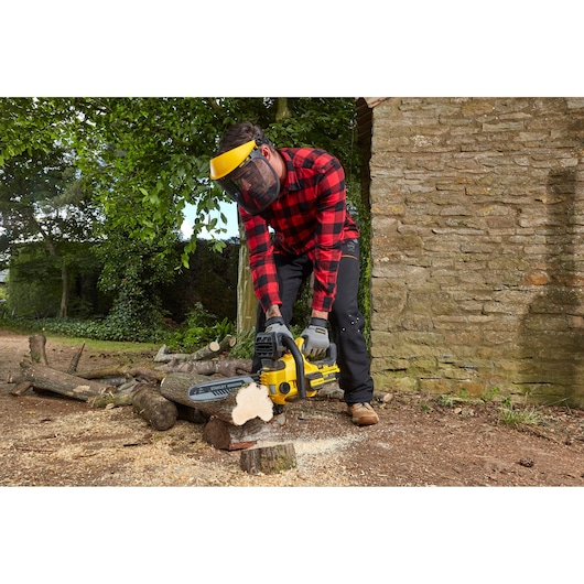 STANLEY SFMCCS630M1 tronçonneuse utilisée en extérieur, coupe du bois, homme portant un équipement de sécurité.
