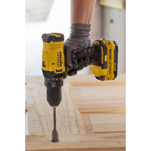 Perceuse sans fil STANLEY SFMCD700C2K jaune et noire, utilisée pour percer du bois avec un foret large.