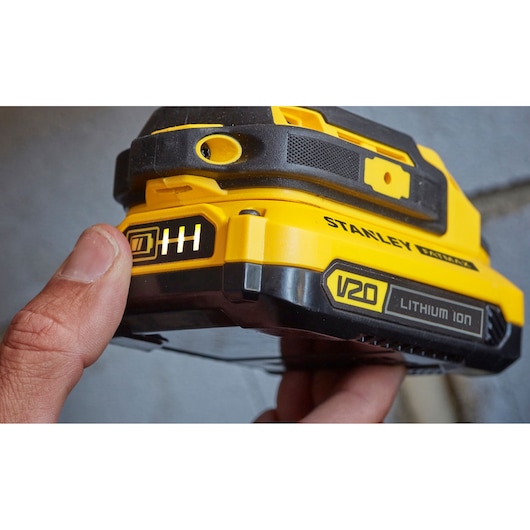 Stanley SFMCD711B V20 Lithium Ion batterij close-up, geel-zwarte behuizing, vinger op indicator.