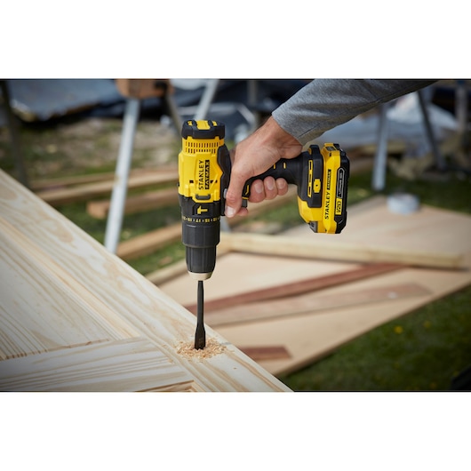 STANLEY SFMCD711B draadloze boormachine gebruikt op hout, close-up van geel en zwart gereedschap.