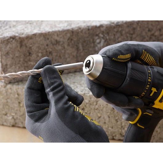 STANLEY SFMCD711B snoerloze boormachine close-up, gehandschoende handen plaatsen boor, buitenomgeving.