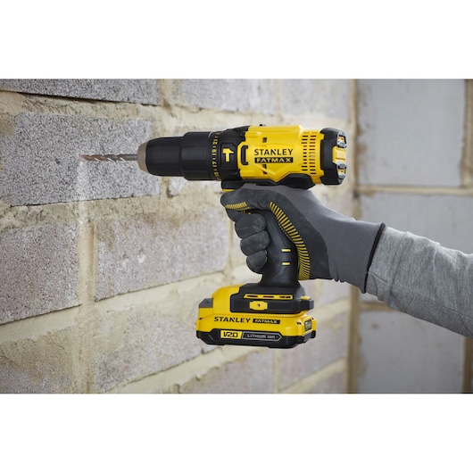 Foto van STANLEY SFMCD711C2S V20 draadloze boormachine gebruikt op een bakstenen muur.