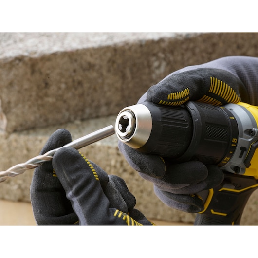 STANLEY SFMCD715C2K draadloze boormachine in gehandschoende handen, metalen boor wordt geplaatst, close-up.
