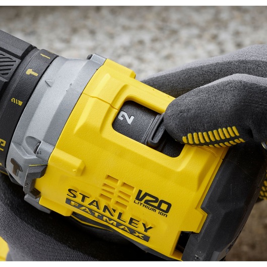 Foto van STANLEY SFMCD715C2K V20 FATMAX accu boormachine close-up, gehandschoende hand stelt snelheidsknop in.