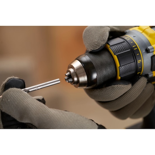 STANLEY SFMCD720D2K perceuse tenue avec des gants, insertion foret, angle rapproché du produit.