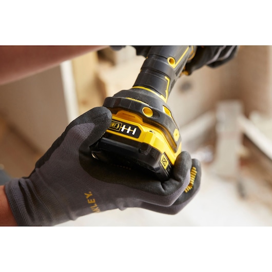 Photo de la perceuse sans fil STANLEY SFMCD720D2K tenue par une main gantée, mise au point sur l’indicateur de batterie.