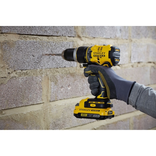 STANLEY SFMCD721B accuboormachine in gebruik op een gemetselde muur, zijaanzicht close-up.